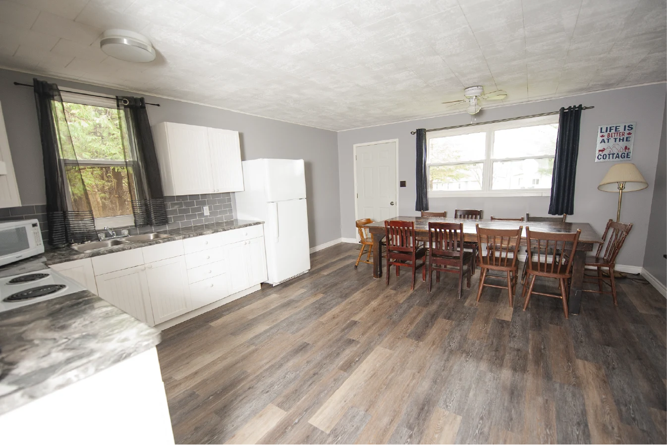 Pigeon Lake Resort Cottage Seven, Spacious kitchen and dining area with long table and multiple chairs in a cottage interior.